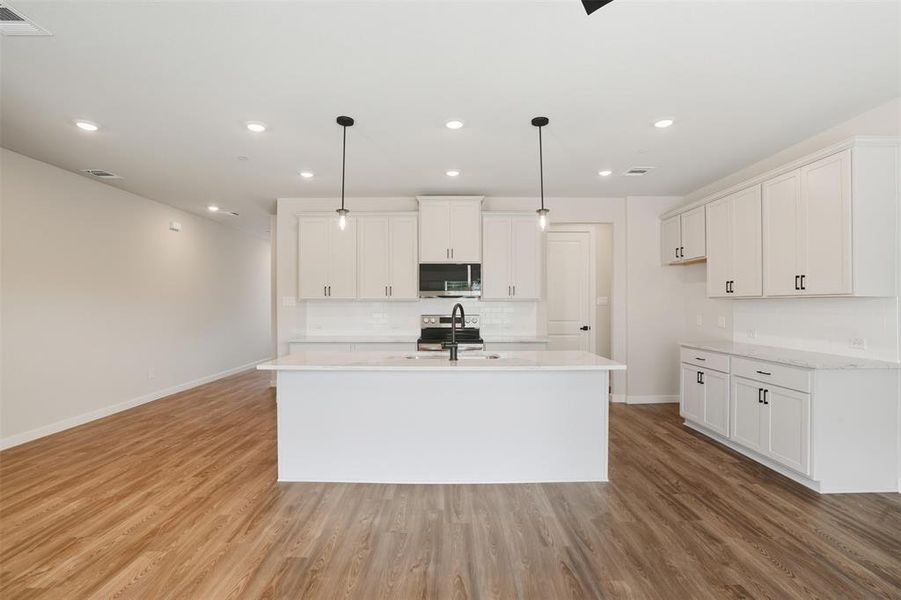 Kitchen with white cabinetry, pendant lighting, a center island with sink, recessed lighting, and backsplash Kitchen with white cabinetry, pendant lighting, a center island with sink, recessed lighting, and backsplash