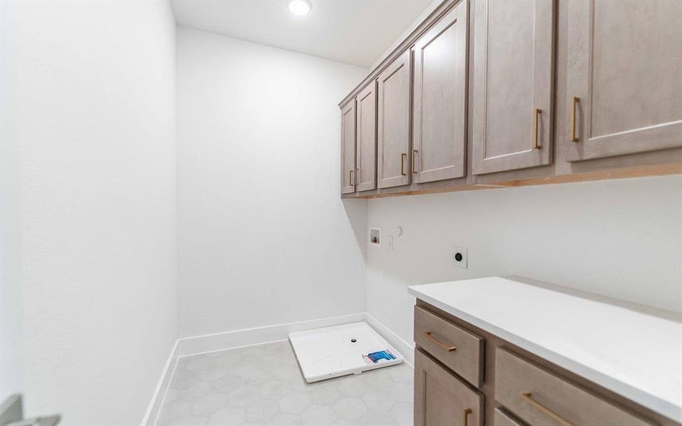 Laundry area with extensive overhead cabinetry, a built-in countertop, and hexagon tile flooring