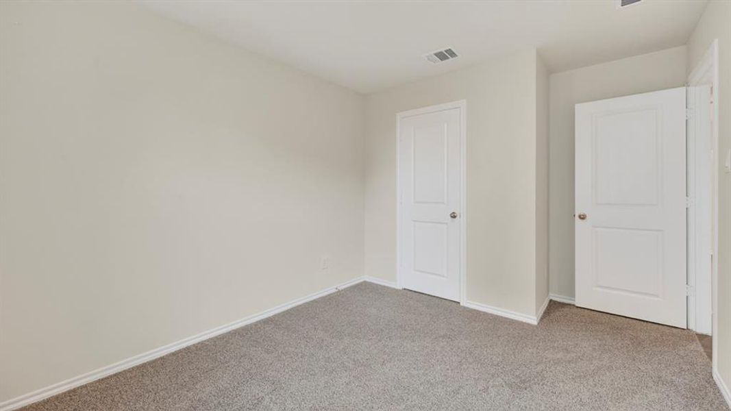 Neutral-toned wall paint and trim, grey carpet flooring, and two paneled doors with silver hardware