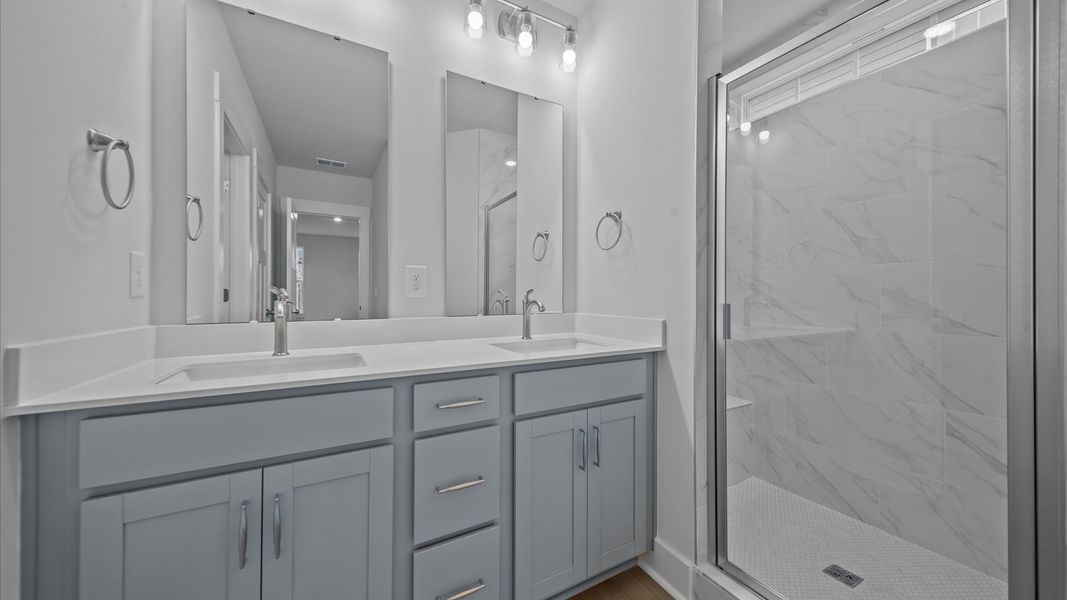 Memorable mornings begin in this elegant primary bathroom with tiled walk-in shower and double vanity Memorable mornings begin in this elegant primary bathroom with tiled walk-in shower and double vanity