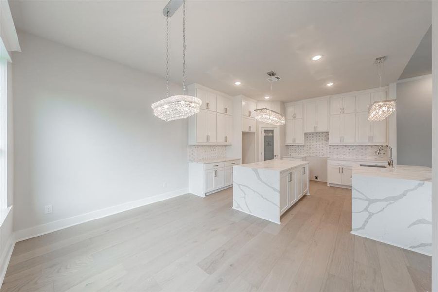 Kitchen featuring a chandelier, light stone counters, decorative backsplash, and recessed lighting