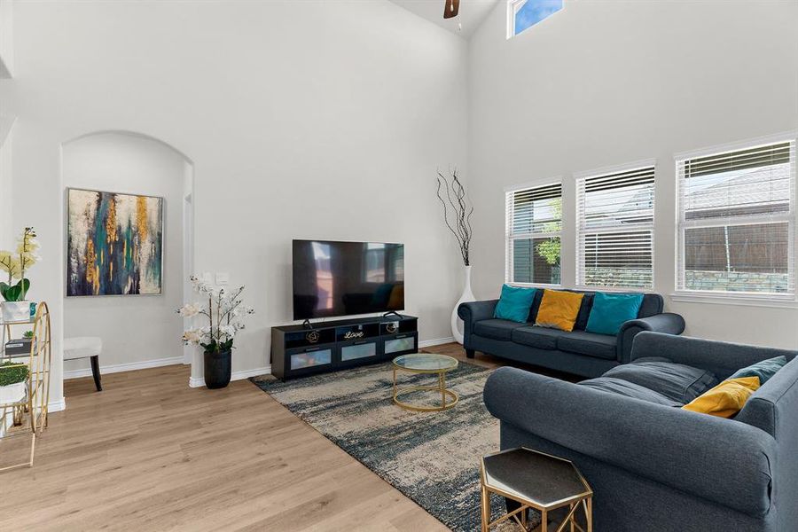 Living area featuring a high ceiling, baseboards, ceiling fan, and wood finished floors