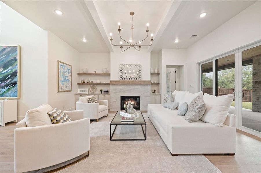 Living room featuring an inviting chandelier, light wood-type flooring, and beam ceiling