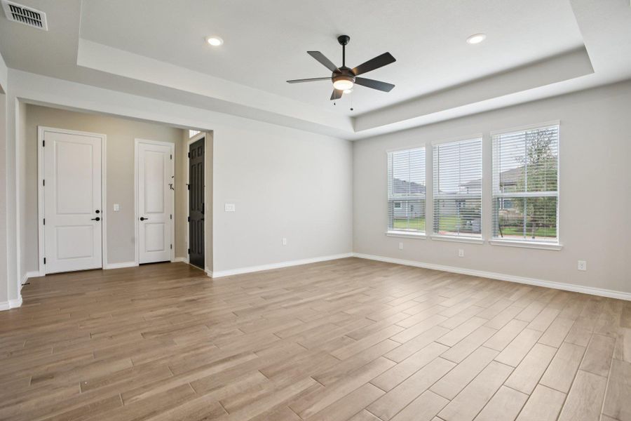 Empty room featuring a raised ceiling, light wood-type flooring, ceiling fan, and recessed lighting Empty room featuring a raised ceiling, light wood-type flooring, ceiling fan, and recessed lighting