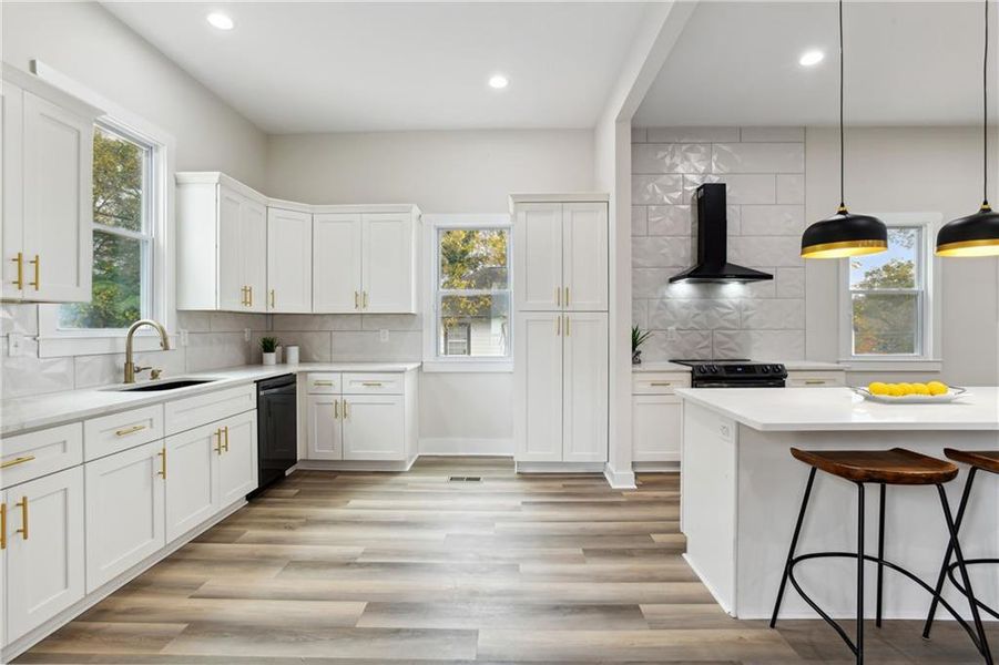 Kitchen with plenty of natural light, hanging light fixtures, wall chimney range hood, and backsplash