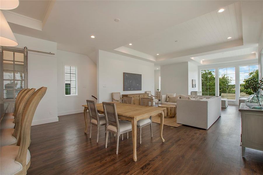 Dining room featuring a healthy amount of sunlight, dark hardwood flooring, and a tray ceiling