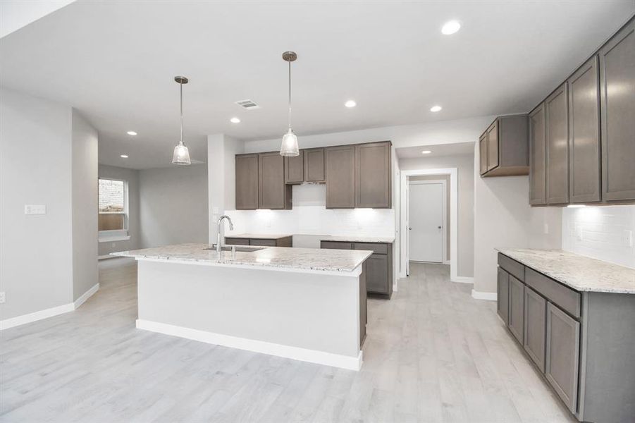 Culinary haven, featuring granite countertops, a tile backsplash, stainless steel appliances (to be installed), and 42” upper cabinets. Sample photo of completed home with similar floor plan. Actual colors and selections may vary.