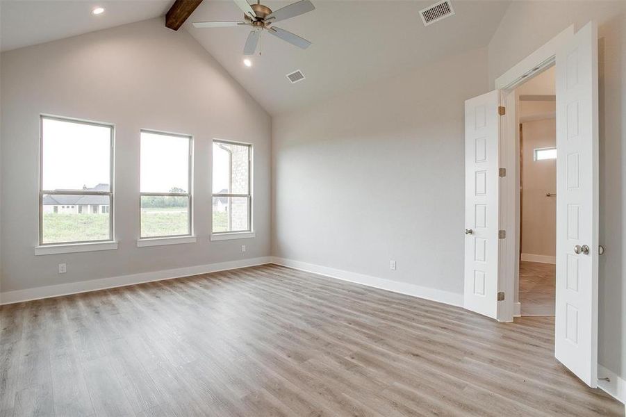 Empty room with high vaulted ceiling, beamed ceiling, ceiling fan, and light wood-type flooring