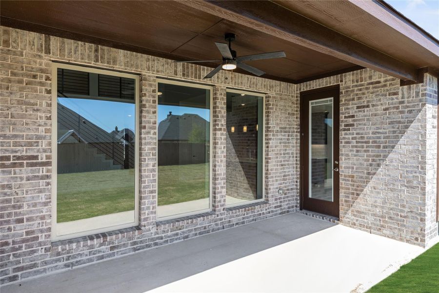 Covered back patio with ceiling fan, brick exterior, large windows, and glass door leading inside Covered back patio with ceiling fan, brick exterior, large windows, and glass door leading inside