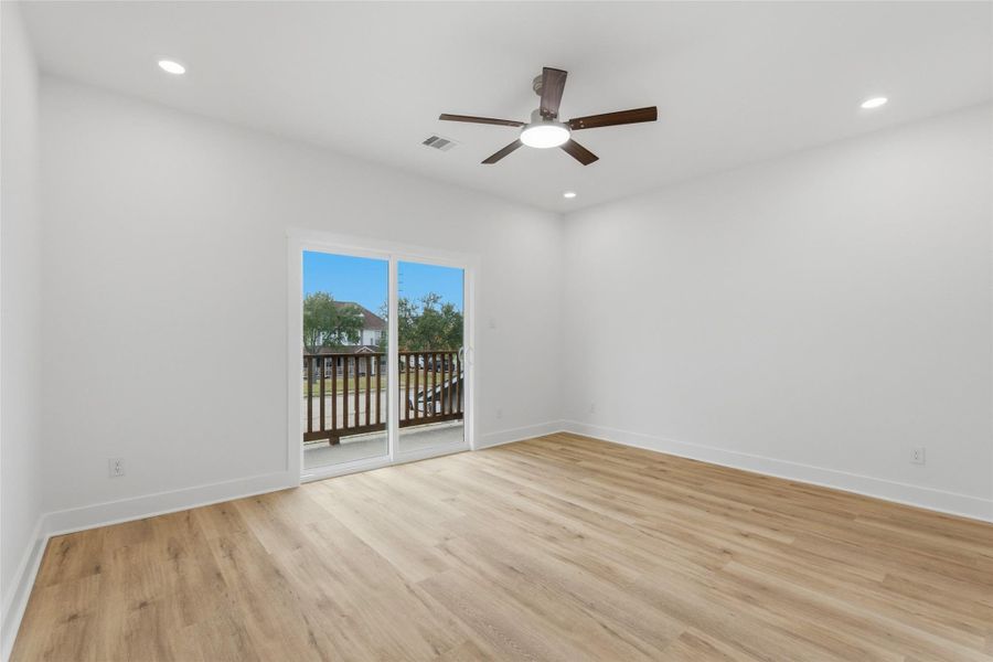 Second-floor primary bedroom with luxury vinyl flooring, ceiling fan, recessed lighting, and a private en suite bathroom.