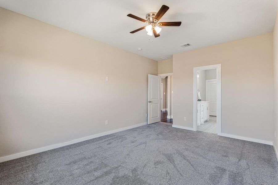 Master bedroom with connected bathroom, ceiling fan, and light colored carpet Master bedroom with connected bathroom, ceiling fan, and light colored carpet