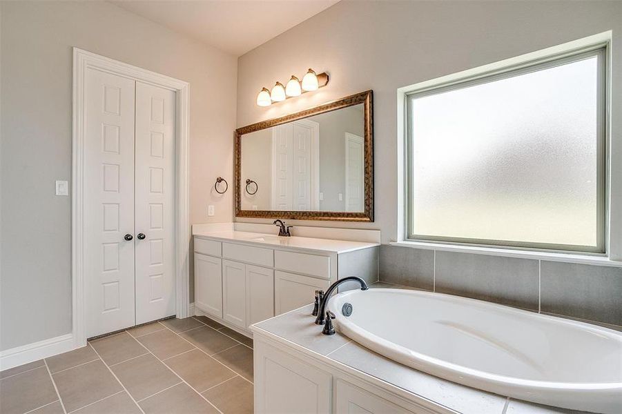 Bathroom featuring tile patterned floors, a bath, and vanity