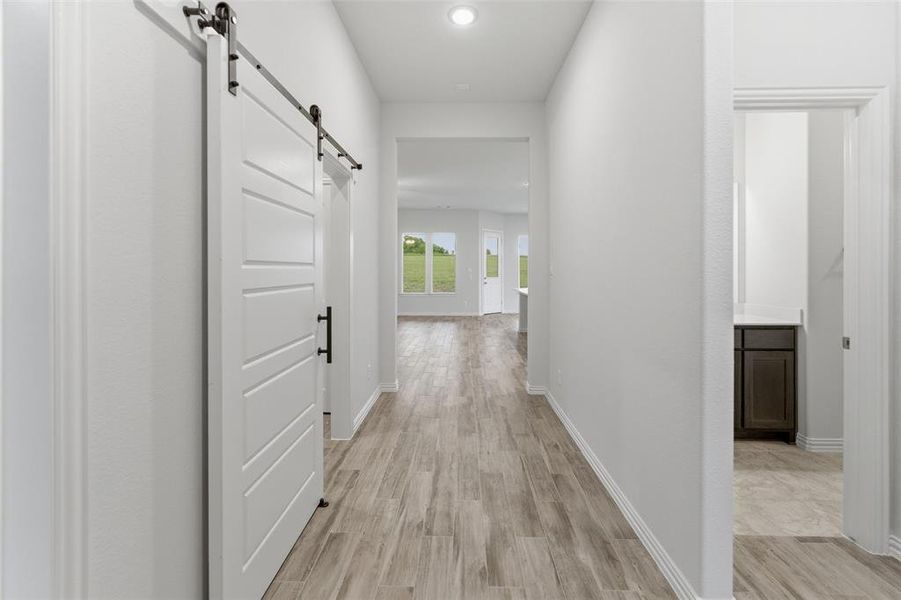 Hallway featuring wood-finish flooring, recessed lighting, and a white barn door with black hardware