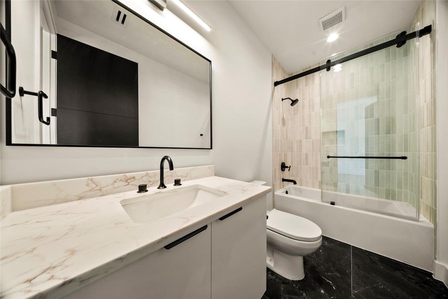 Full bath with vanity, combined bath / shower with glass door, and dark marble finish floors Full bath with vanity, combined bath / shower with glass door, and dark marble finish floors