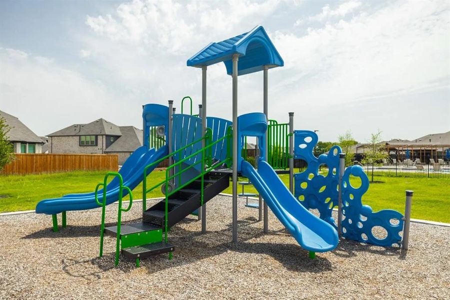 Playground structure featuring multiple blue slides, climbing elements, and a covered platform