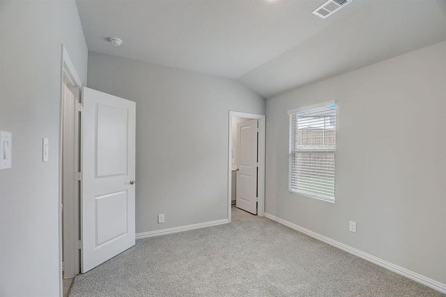 Unfurnished bedroom with light carpet and lofted ceiling