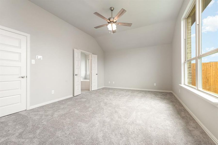 Unfurnished bedroom with lofted ceiling, light carpet, ceiling fan, and connected bathroom