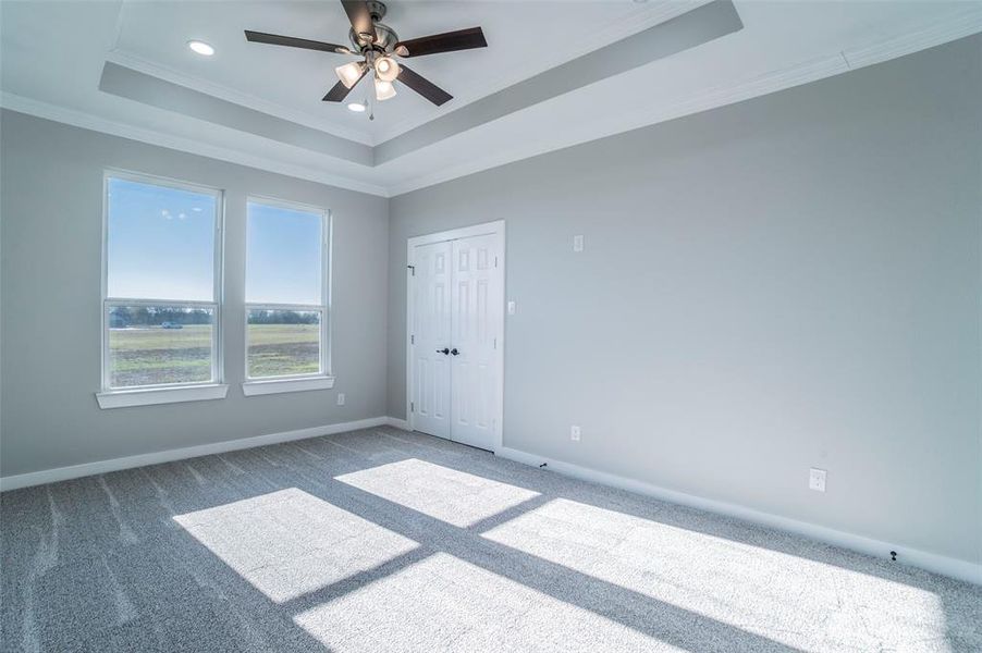 Carpeted empty room with ornamental molding, a raised ceiling, a ceiling fan, and recessed lighting Carpeted empty room with ornamental molding, a raised ceiling, a ceiling fan, and recessed lighting