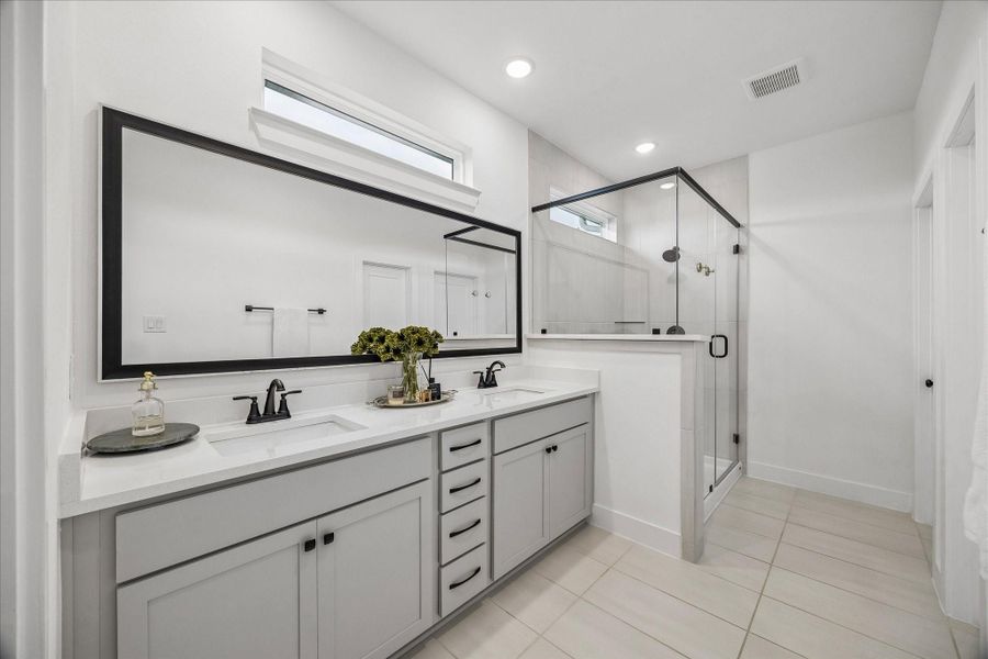 The primary bath features a double-sink quartz vanity, transom windows, a frameless glass walk-in shower, and a spacious walk-in closet.