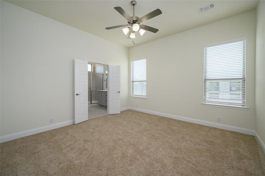 Unfurnished bedroom with ensuite bathroom, carpet flooring, and ceiling fan