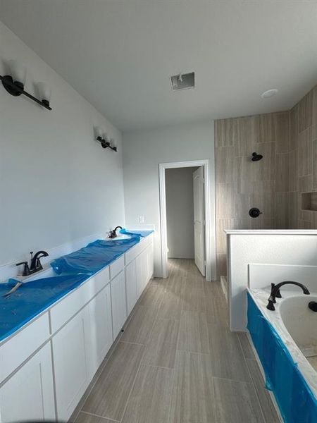 Full bath with double vanity, walk in shower, and a garden tub