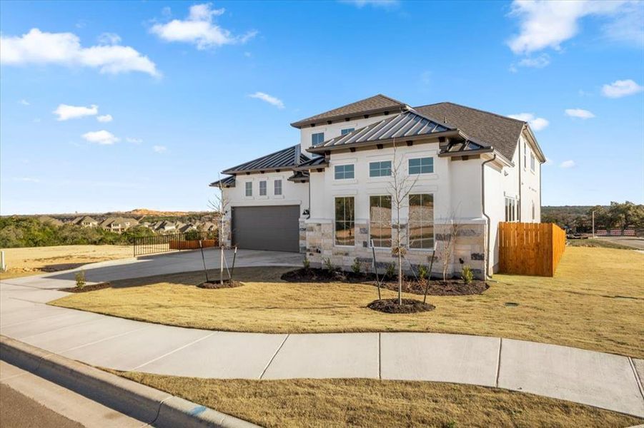 View of front of property with driveway, a standing seam roof, and stone siding