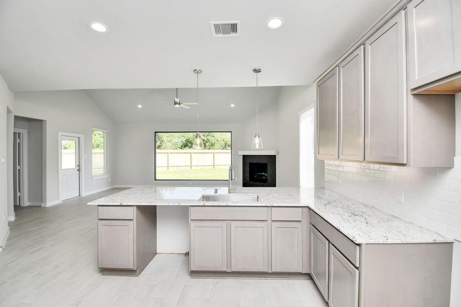 This generously spacious kitchen is a dream realized! With a massive granite island, high ceilings, soft close cabinets, granite countertops, stainless steel appliances, a sleek tile backsplash, recessed lighting, and an extended counter area, it offers both style and practicality. All this opens up to the expansive family room, creating a perfect hub for gatherings. Sample photo of completed home with similar floor plan. Actual colors and selections may vary.