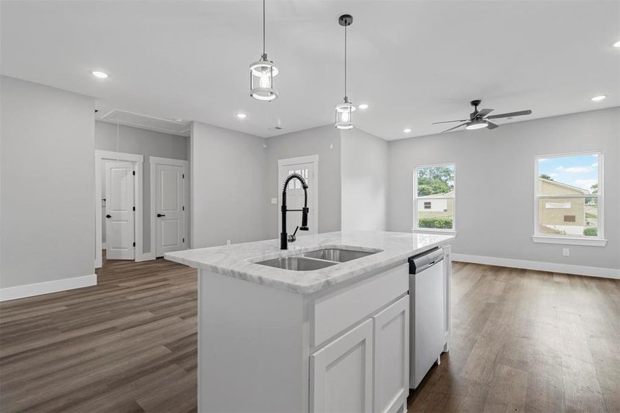 Kitchen featuring decorative light fixtures, dark hardwood / wood-style flooring, dishwasher, a center island with sink, and sink