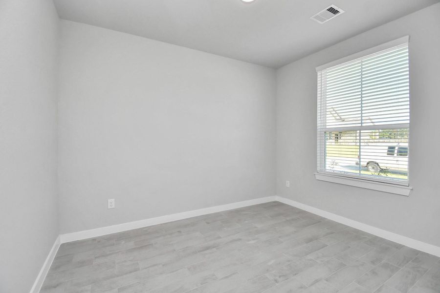 Experience the perfect blend of sophistication and warmth in this home office, boasting elegant wood-look tile flooring and flooded with natural light from expansive windows and French doors. Sample photo of completed home with similar floor plan. Actual colors and selections may vary.