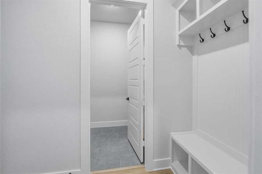 Entryway featuring white built-in storage with hooks and shelving, and a bench with open storage below