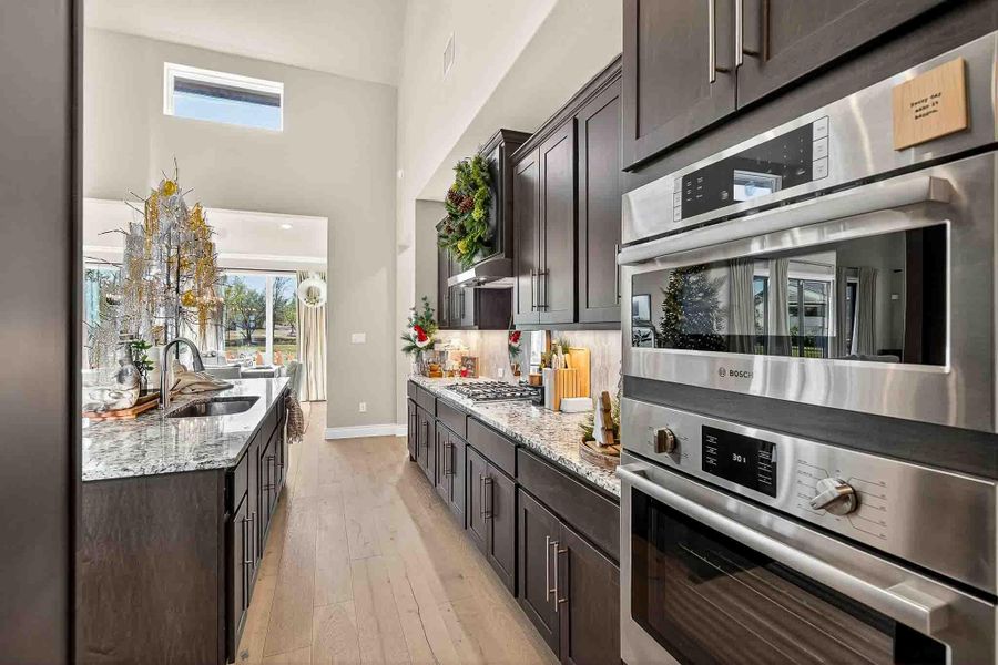 Kitchen with stainless steel appliances, plenty of natural light, light stone countertops, and a high ceiling