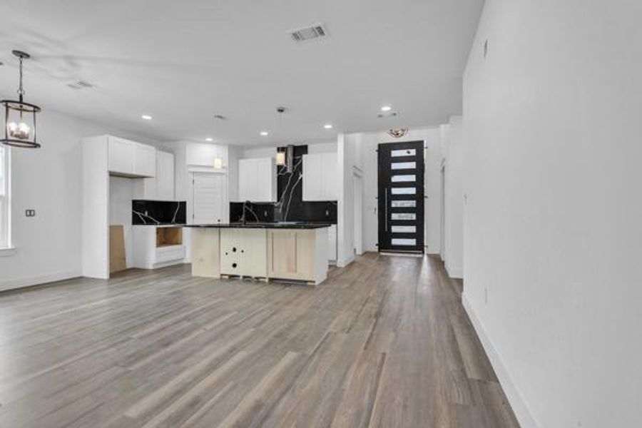 Kitchen with dark countertops, light wood-type flooring, white cabinets, open floor plan, and recessed lighting