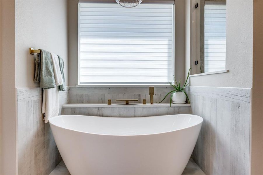 Bathroom featuring wainscoting, a freestanding bath, and healthy amount of natural light