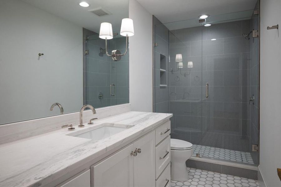 Bathroom with vanity, toilet, an enclosed shower, and tile patterned flooring