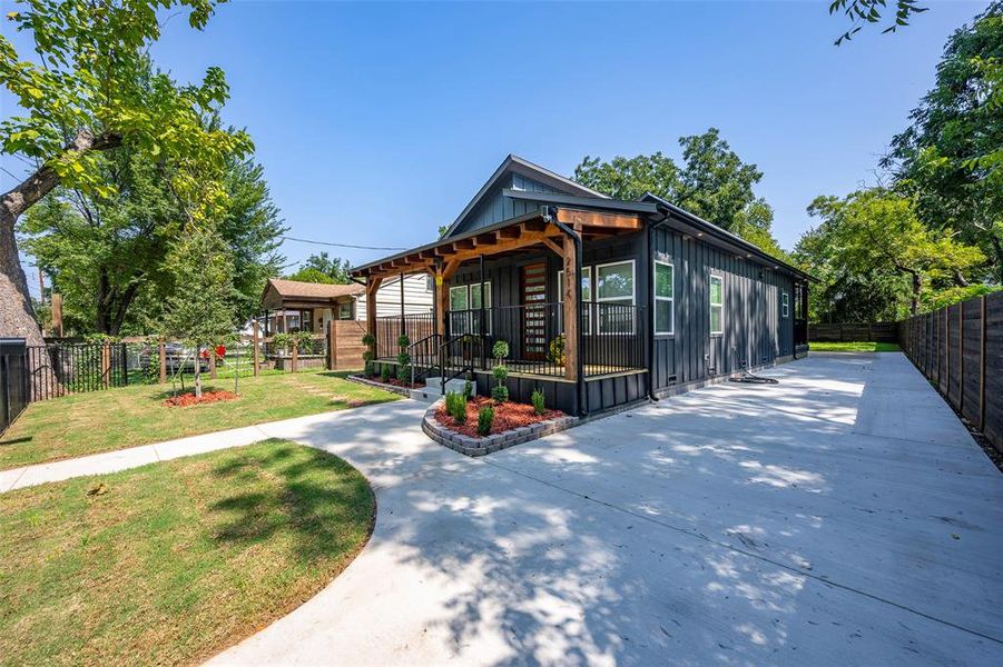 View of front of house with board and batten siding, driveway, and covered porch