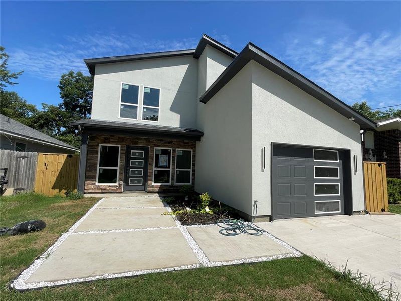 Contemporary home featuring an attached garage, stucco siding, and concrete driveway Contemporary home featuring an attached garage, stucco siding, and concrete driveway