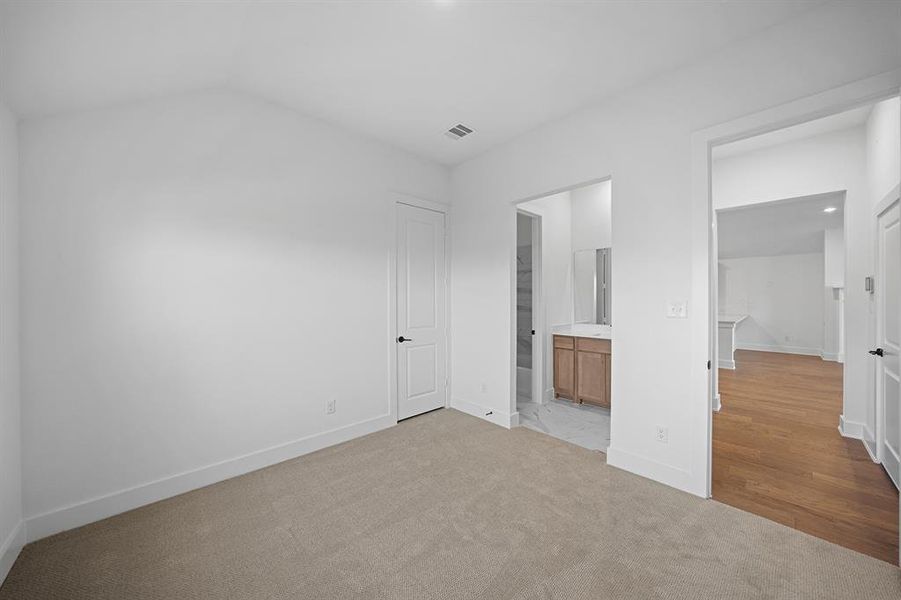Unfurnished bedroom featuring light carpet and ensuite bathroom Unfurnished bedroom featuring light carpet and ensuite bathroom