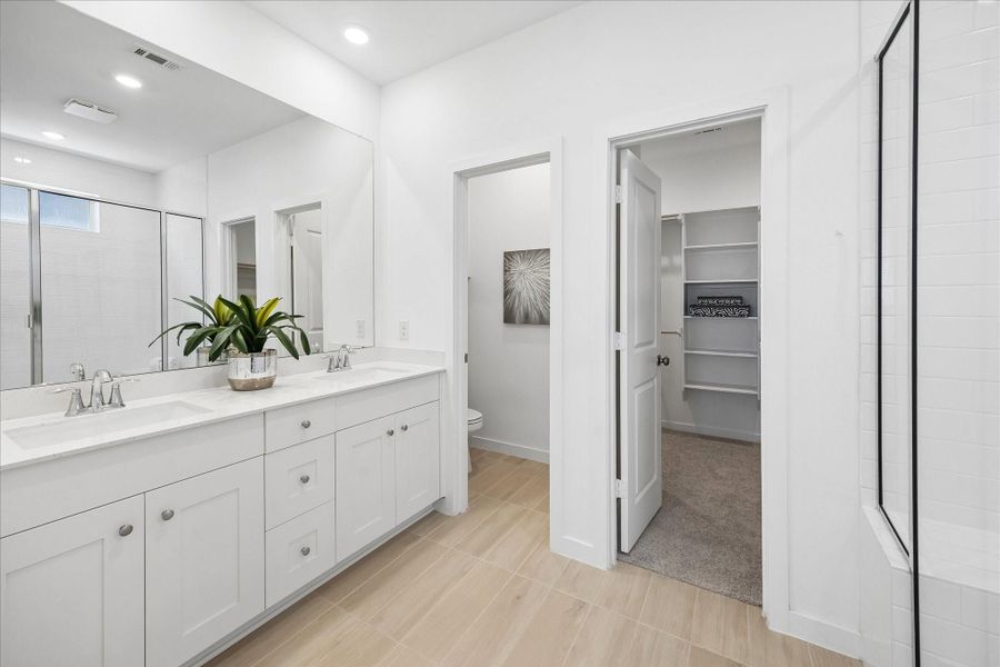 Start and end the day with a little extra luxury in this spa inspired ensuite, where a long dual sink vanity, extensive storage, crisp clean finishes and wood look tile flooring create a bright, polished retreat.