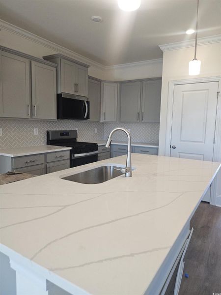 Kitchen featuring gray cabinetry, tasteful backsplash, crown molding, light stone countertops, and range with gas cooktop