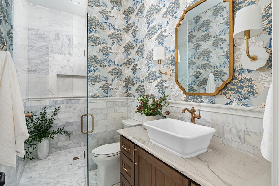 Full bathroom featuring vanity, wainscoting, a shower stall, and Carrera tile walls