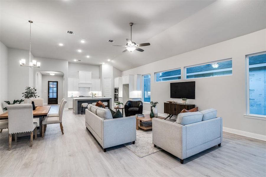 Living room featuring ceiling fan with notable chandelier, light hardwood / wood-style floors, lofted ceiling, and sink