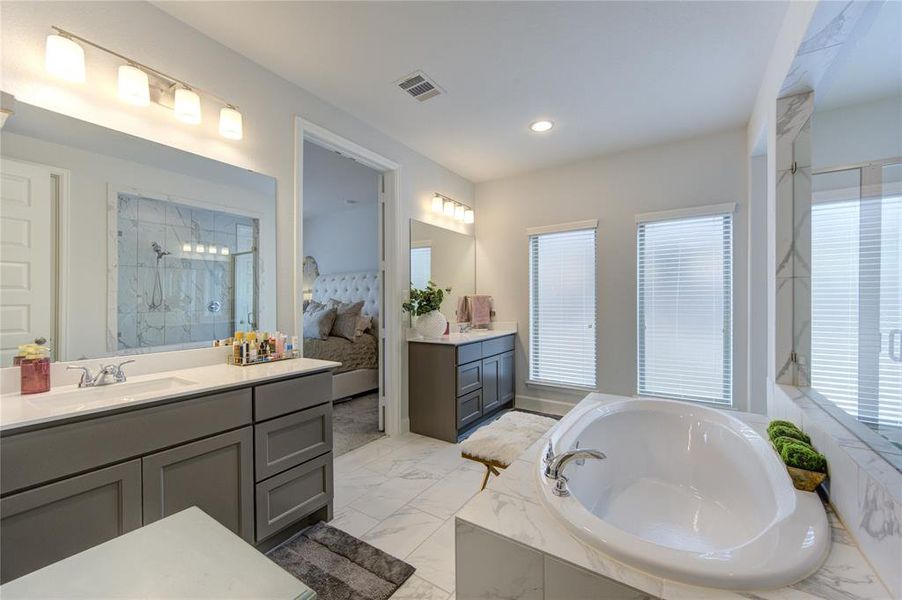 Two individual vanity areas with rich cabinet colors and moder lighting enhaces the primary bathroom.