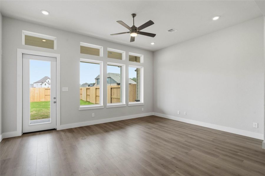 Soaring, tall windows frame the living space, bathing the room in natural light and highlighting the architectural volume of the space. A convenient back door provides direct and easy access to a comfortable covered patio, effortlessly extending your living space outdoors for year-round enjoyment and entertaining.