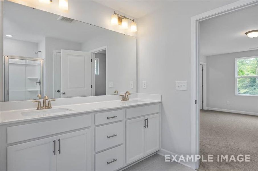 Bathroom with baseboards, visible vents, a sink, and double vanity