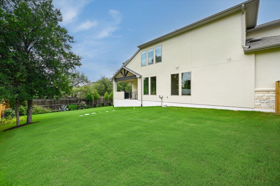 A spacious backyard with mature trees provides ample green space for outdoor activities and relaxation.