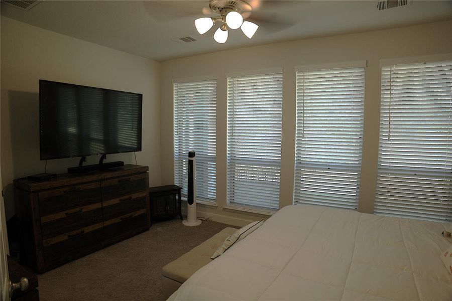 Carpeted bedroom featuring a ceiling fan Carpeted bedroom featuring a ceiling fan
