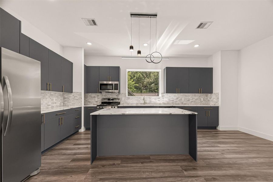 This modern kitchen features sleek gray cabinetry, a central island with a marble-style countertop, and stainless steel appliances. The space is enhanced by vinyl flooring, recessed lighting, and a large window providing natural light. This modern kitchen features sleek gray cabinetry, a central island with a marble-style countertop, and stainless steel appliances. The space is enhanced by vinyl flooring, recessed lighting, and a large window providing natural light.