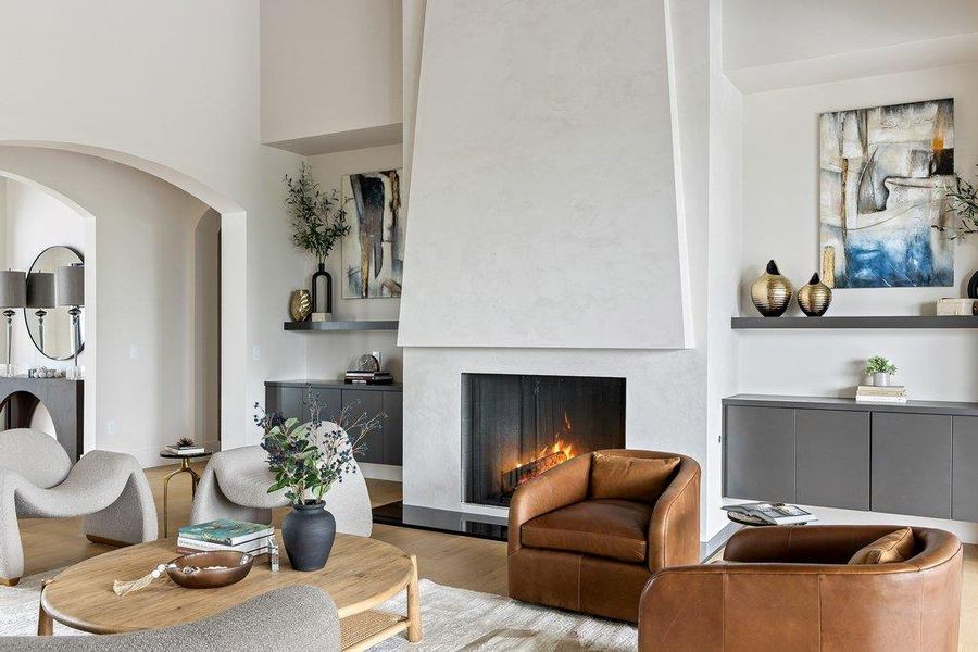 Living space featuring a tall, angular fireplace with a dark firebox, flanked by built-in cabinetry and floating shelves