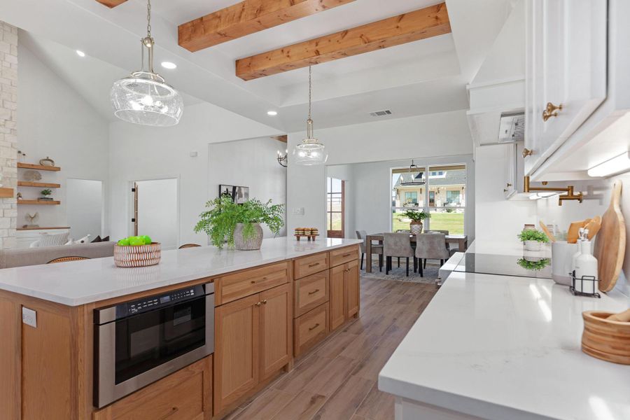 Two tone kitchen with a spacious island, light stone countertops, light wood-type flooring, hanging light fixtures, and two tone cabinetry Two tone kitchen with a spacious island, light stone countertops, light wood-type flooring, hanging light fixtures, and two tone cabinetry