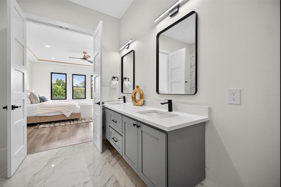 Full bathroom featuring double vanity, light marble finish flooring, ceiling fan, and ensuite bathroom